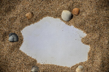 Blank white sheet of paper on white sand with seashells and stones. Message by the sea, romance, valentine's day, mother's day, father's day. Copy space