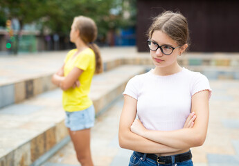 Two young girls having quarrel between each other in city park.