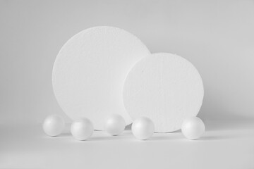 Two round 3d stands, of different sizes, on white isolated background, surrounded by balls. Concept of geometric composition on white isolated background