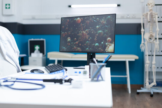 Empty hospital office having computer on table with coronavirus cell on screen during virus examination. Medical room with nobody in it equipped with professional tools. Virus illustration