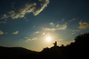 Silhouette of a girl during sunset in the mountains. The concept of victory, achievement and perfection.