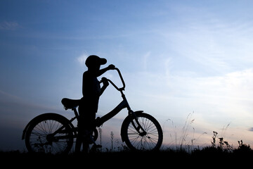 Fototapeta na wymiar silhouette of a boy on a bicycle in nature