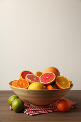 Bowl with citrus fruits on wooden table