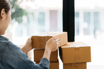 Asian woman start up small business owner packing cardboard box at workplace. freelance woman...