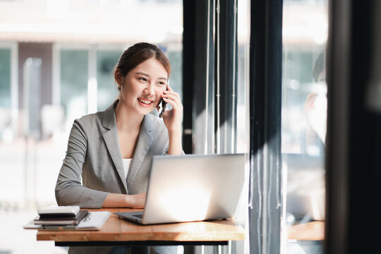 Portrait Of Young Asian Business Woman Talk On Smartphone Write Notebook Laptop In Home Office. Beautiful Girl At Desk Computer Take Home Order. Startup Business Asia Woman Online Sme Telemarketing.