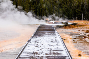 Wooden walkway covered by snow inside heat area of Yellowstone.