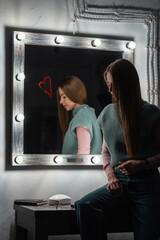 Fototapeta na wymiar beautiful girl in vintage fashion sits near a mirror with lamps in the dark.