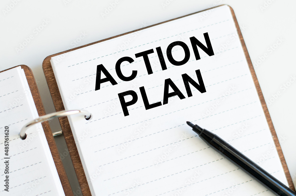 Poster action plan text on notepad next to a black marker on the table