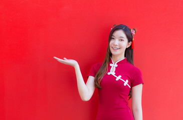 Asian beautiful woman in long hair wears a red Chinese dress or qipao on  red background with...