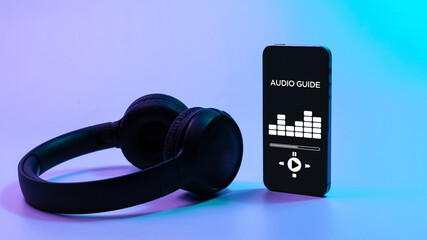 Audio guide online app on digital mobile smartphone screen with music headphones on neon...