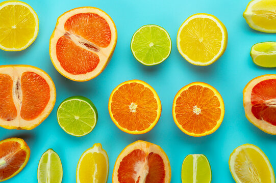 slices of yellow lemon, green lime, orange orange, red grapefruit on a blue background. fruit background image