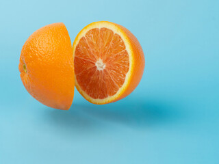 two halves of a cut orange hang in the air on a blue background. Juicy orange cut in half