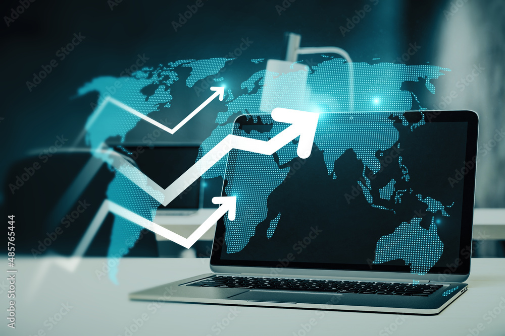 Poster Close up of office desktop with laptop and abstract glowing growing business arrow and map hologram on blue background. Technology and internet data concept. Double exposure.