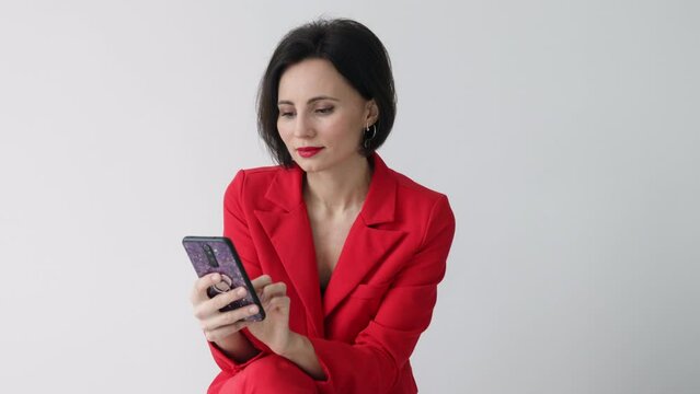 35s nice-looking attractive gorgeous charming cheerful woman using phone on the white wall background texting message scrolling tapping technology isolated lifestyle. Mock up copy space. 