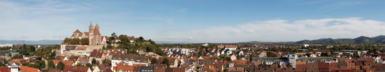 Obraz premium Panoramablick auf die Altstadt Breisach am Rhein mit Münster an Münsterberg und Breisacher Burgberg. Im Hintergrund links Vogesenmassive und nach rechts der Kaiserstuhl verlaufend der Schwarzwald