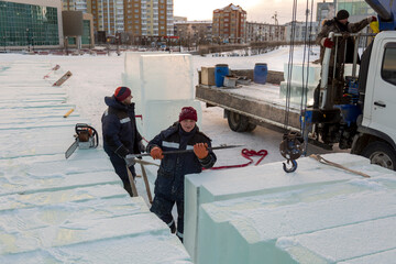 An assembly worker tries to push the ice slabs apart with a crowbar