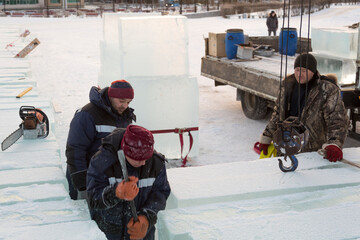 An assembly worker tries to push the ice slabs apart with a crowbar