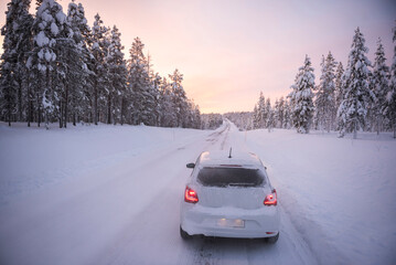 Car driving on icy snow covered roads on a road trip while travelling in Lapland inside the Arctic...