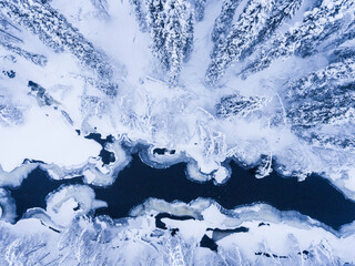Aerial of frozen river and snow covered forest winter landscape showing amazing Lapland scenery in Scandinavia in Finland drone
