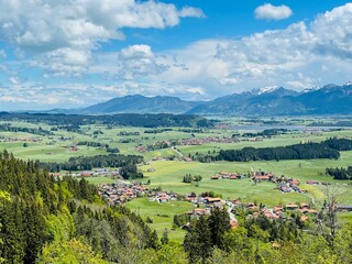 Blick über das Allgäuer Alpenvorland und mehreren Dörfern zum Füssener Alpenmassiv