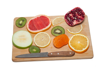 Cut the fruit into slices on a wooden board. persimmon. yellow lemon. kiwi, green kiwi. Walnut. red pomegranate. bunch of grapes. cinnamon. knife. place for text. fruit concept