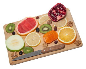 Cut the fruit into slices on a wooden board. persimmon. yellow lemon. green kiwi. red pomegranate. orange. pear. table-knife. fruit concept. on white background