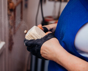 A female carpenter grinds wood with special equipment in a carpentry or homemade workshop. Dust and...