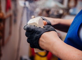 A female carpenter grinds wood with special equipment in a carpentry or homemade workshop. Dust and...