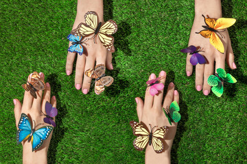 Spring creative layout with colorful butterflies on hands against bright green grass background....
