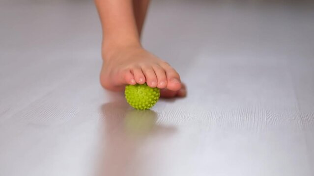 Little boy massaging with ball his foot. Feet Massage Using Trigger Point Spiky Massage Ball. Myofascial Release. close up. Shot video. Slow motion