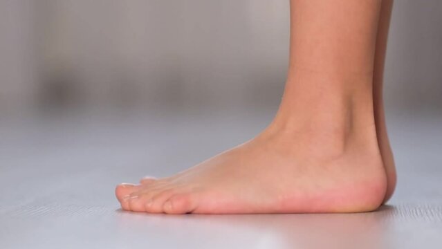 Children's bare feet. Child's bare feet on the wooden floor. Prevention of flat feet in children. Exercises for the legs. Flat feet physical therapy. close up Shot video. Slow motion
