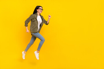 Fototapeta na wymiar Full body profile photo of cool young lady run wear eyewear shirt jeans footwear isolated on yellow background