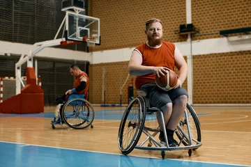 Fotobehang Disabled athlete in wheelchair on basketball sports court looking at camera. © Drazen