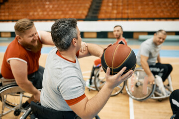 Rear view of wheelchair-bound basketball player avoiding his opponent during the match on sports...