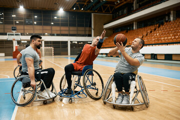 Fototapeta na wymiar Group of wheelchair-bound players playing basketball match on sports court.