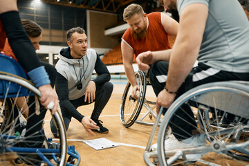 Coach of wheelchair basketball discusses with his team about match strategy.