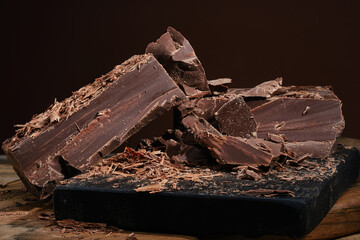 Composition of bars and pieces dark chocolate with chocolate chips on a wooden cutting board....
