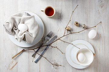 Table setting and decoration for Easter. White and partridge eggs in a plate with a napkin. poplar...
