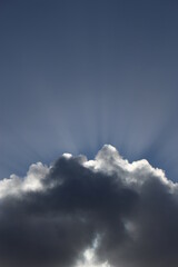 Sun bursting out of a fluffy white cloud. Wallpaper, background or graphic resource concept