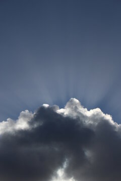 Sun bursting out of a fluffy white cloud. Wallpaper, background or graphic resource concept