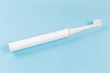 Electric rechargeable toothbrush on a blue surface