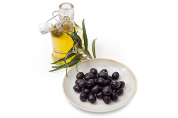 Canned olives on saucer against olive branch and olive oil
