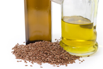 Heap of linseeds against different oil bottles, fragment close-up