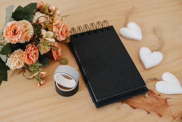 notebook with black sheets with copy space, bouquet of flowers and a white heart.