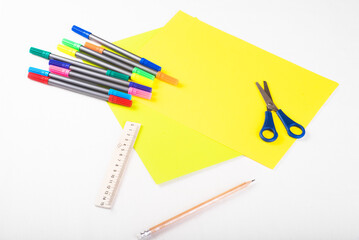 Set of color papers, scissors, ruler, felt-tip pens and pencil for creative work on white background. Top view. Flatlay