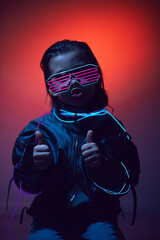 portrait cyberpunk boy child in neon glasses in blue and red tones with wires on a red background