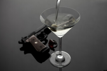 Vodga Martinti im Cocktailglas mit Pistole und Ring im Hintergrund