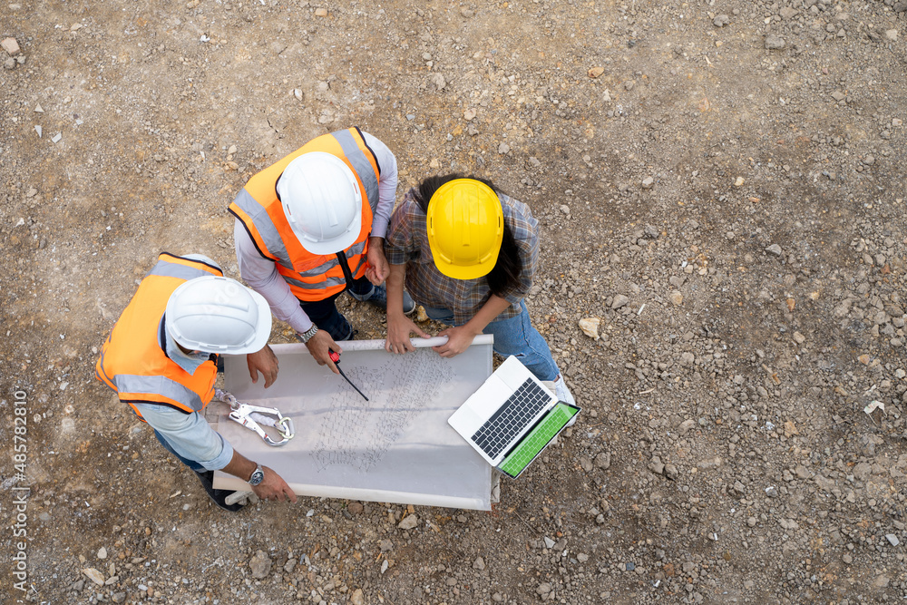 Poster top view of architectural engineer working on his blueprints with documents on a building site.