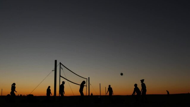 Volleyball net silhouette on beach sport court at sunset, people playing on California coast, USA. Sport field for volley ball game players by ocean shore. Twilight sky of Mission beach, San Diego.