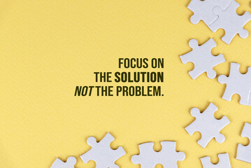Motivational quote - Focus on the solution not the problem. With white jigsaw puzzle background on soft yellow background. Life and business solution concept.
